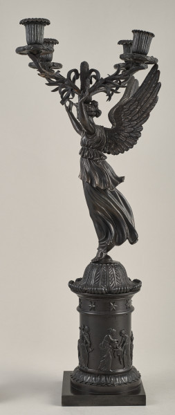Kandelabr 4 świecowy, ciemny w formie uskrzydlonej postaci na postumencie trzymającej w górze ramiona świecznika.Bok prawy