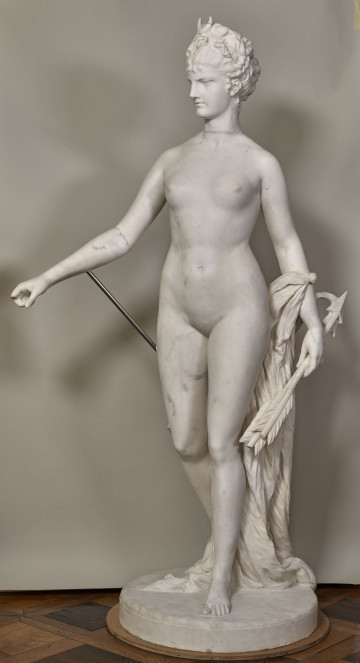 Diana. Marmurowy posąg przedstawia stojącą na wprost nagą, smukłą kobietę z głową zwróconą w prawo.