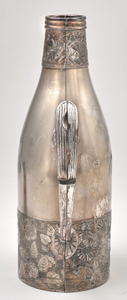 Srebrne etui na butelkę, zamknięte, ukazane od strony ucha. Pas roślinnej dekoracji u dołu i u góry etui