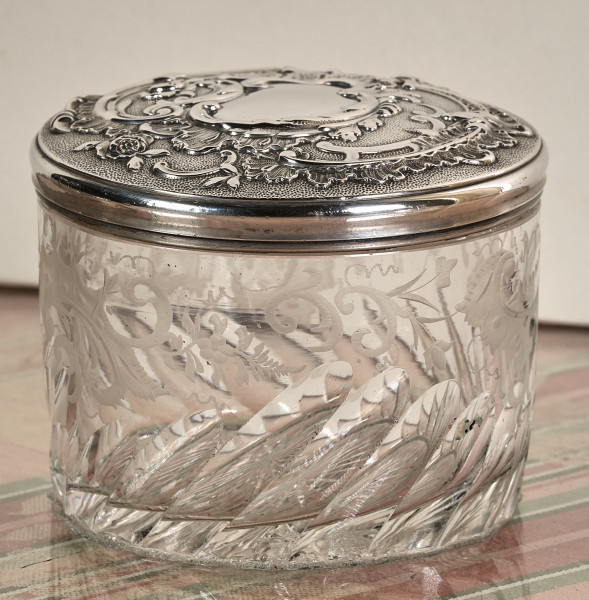 Puzderko ze szkła kryształowego ze srebrną pokrywką. Szkło i pokrywka bogato dekorowane wzorami roślinnymi.