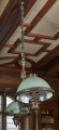 Dekoracyjna lampa wisząca z szeroko rozstawionymi kloszami na tle drewnianej boazerii i kasetonowego sufitu
