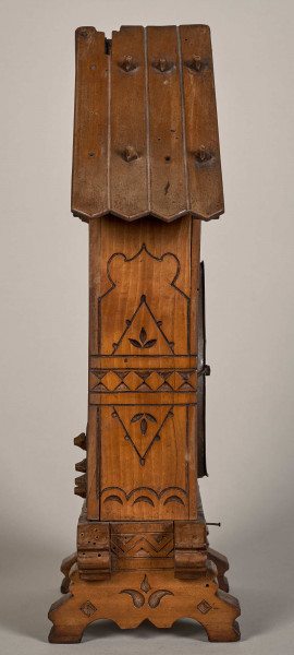 Bok zegara w formie drewnianej chatki.