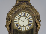 zbliżenie na dekorację rzeźbiarską zegara z przodu - twarz Meduzy w otoczeniu zwojów roślinnych