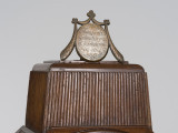 zbliżenie na dekorację zwieńczenia zegara - mosiężny medalion z rytowana łacińską sentencją: TEMPORA MUTANTUR IN ILLIS
