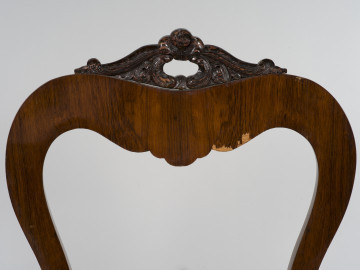 zbliżenie na zdobienie zwieńczenia fotela - ornament ażurowy rzeźbiony w ciemnym drewnie, łączący stylizowane elementy roślinne