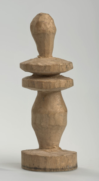 Ujęcie z boku [4]. Ze względu na swój okrągły kształt kolejne ujęcia z boku nie różnią się między sobą znacząco. Goniec został wykonany ręcznie z kawałka jasnego drewna. Na całej powierzchni widoczne są ślady rzeźbienia przy pomocy noża. Obiekt w kolorze naturalnego drewna (nie został pomalowany, ani polakierowany). Od spodu widoczne oznaczenie składające się z dwóch przecinających się ze sobą linii („X”), które umożliwia podzielenie bierek pomiędzy dwóch graczy - wszystkie bierki są w jednakowym kolorze. Krawędź podstawy została dodatkowo obrysowana ołówkiem. Goniec składa się ze spłaszczonej podstawy w formie krążka, środkowej części w formie walca rozszerzającego się po środku wysokości, dwóch spłaszczonych cylindrycznych elementów, które zwężają się stopniowo ku górze oraz ku dołowi (przypominając dwa połączone ze sobą talerze, z których każdy skierowany jest dnem do zewnątrz; elementy są umieszczone bezpośrednio jednej nad drugim) oraz zwieńczenia o prostej, rozszerzającej się ku górze formie (przypominającej pałkę).