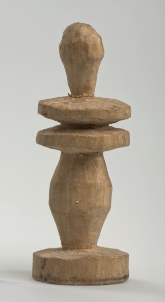 Ujęcie z boku [3]. Ze względu na swój okrągły kształt kolejne ujęcia z boku nie różnią się między sobą znacząco. Goniec został wykonany ręcznie z kawałka jasnego drewna. Na całej powierzchni widoczne są ślady rzeźbienia przy pomocy noża. Obiekt w kolorze naturalnego drewna (nie został pomalowany, ani polakierowany). Od spodu widoczne oznaczenie składające się z dwóch przecinających się ze sobą linii („X”), które umożliwia podzielenie bierek pomiędzy dwóch graczy - wszystkie bierki są w jednakowym kolorze. Krawędź podstawy została dodatkowo obrysowana ołówkiem. Goniec składa się ze spłaszczonej podstawy w formie krążka, środkowej części w formie walca rozszerzającego się po środku wysokości, dwóch spłaszczonych cylindrycznych elementów, które zwężają się stopniowo ku górze oraz ku dołowi (przypominając dwa połączone ze sobą talerze, z których każdy skierowany jest dnem do zewnątrz; elementy są umieszczone bezpośrednio jednej nad drugim) oraz zwieńczenia o prostej, rozszerzającej się ku górze formie (przypominającej pałkę).