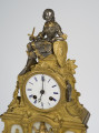 zbliżenie na zwieńczenie zegara - figurka siedzącej na kamieniu Joanny d'Arc w zbroi