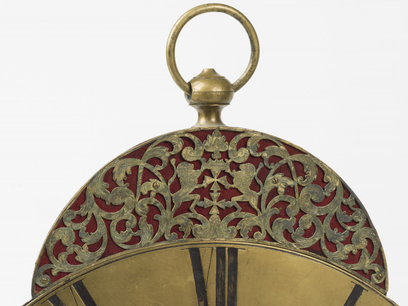 zbliżenie na dekoracyjne zwieńczenie zegara - ażur z herbem Gdańska, nad nim pierścień pozwalający zawiesić zegar na ścianie