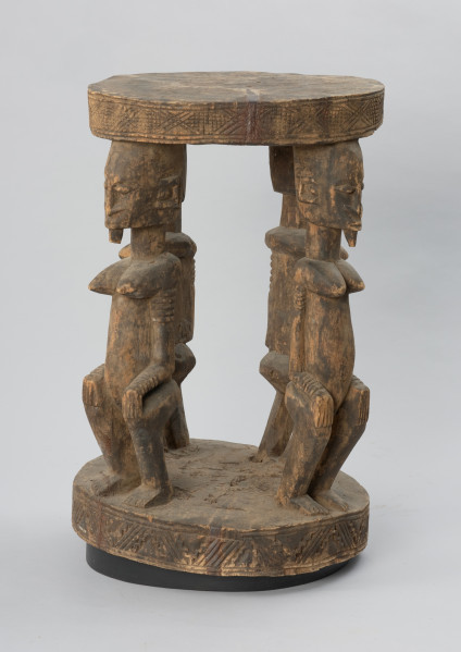 rzeźba - Ujęcie prawego boku. Drewniany stół. Okrągły blat połączony z podstawą o tym samym kształcie za pomocą czterech rzeźbionych postaci.
