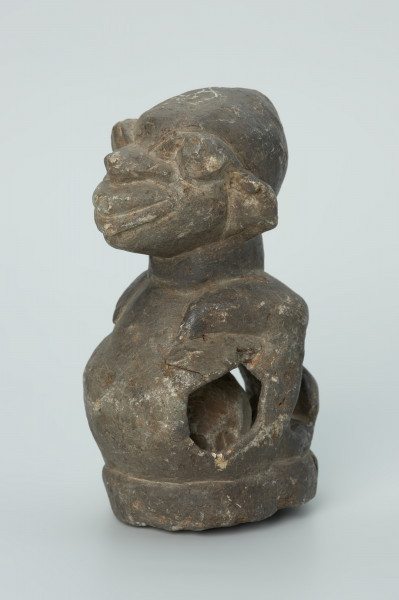 rzeźba; przedmiot obrzędowy; Figura kultu sił wegetacji - Ujęcie z przodu z lewej strony. Rzeźbiona w grafitowym steatycie półpostać o cechach ciężarnej kobiety. W dużym, wydętym brzuchu z czterema otworami umieszczona jest kamienna kula.