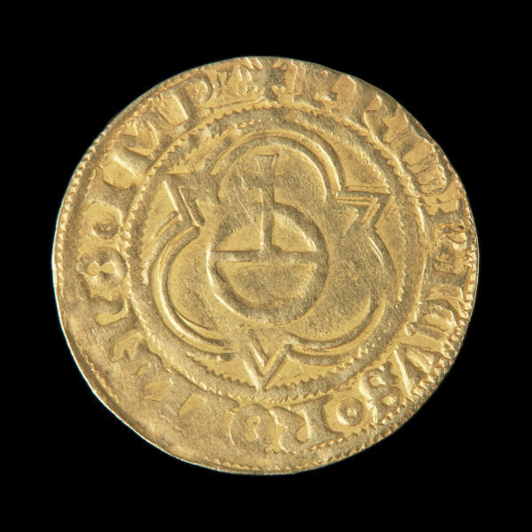 skarb monet - Ujęcie rewersu jednej ze złotych monet ze skarbu. Skarb 656 szelągów krzyżackich i 2 guldenów niemieckich ukryty w kaflu piecowym pod koniec XV wieku.