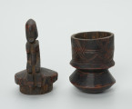 drewninany pojemnik na tytoń z pokrywką - Ujęcie z przodu, z rozłożonymi osobno częściami. Drewniany pojemnik na tytoń z pokrywą, na której znajduje się rzeźbiona, siedząca postać.