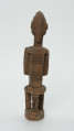 drewniana, rzeźbiona figura - Ujęcie z tyłu. Drewniana, rzeźbiona figura kobiety siedzącej na stołku.