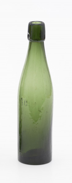 szklana butelka bez wyodrębnionej szyjki - Ujęcie z tyłu; Butelka piwówka z grubego szkła butelkowego w ciemnym kolorze oliwkowo-zielonym. Brak wyodrębnionej szyjki, ktora zakończona jest u wylotu pierścieniem z dwoma otworami do zamknięcia pałąkowego (brak). Dno wklęsłe.