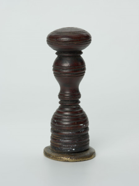 łłok pieczętny - Ujęcie z boku; Drewniana bogato ryflowana rękojeść trzymająca okrągłą pieczęć.