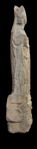 Biskup Otto z Bambergu - Ujęcie z lewej strony; Rzeźba wykonana jest w jednym bloku piaskowca. Przedstawia pełnoplastycznie opracowaną postać w stroju biskupa stojącego na płaskorzeźbionej przyściennej konsoli. Biskup na głowie nosi niską mitrę. Narzucony na ramiona płaszcz spięty jest czterolistną zapinką dekorowaną przedstawieniem gryfa. W zgiętych w łokciu rękach trzyma: w prawej panniselus, w lewej księgę lub fragment budowli (kształt o nieczytelnej formie). Powierzchnia szat w górnej partii rzeźby gładka, poniżej rąk, modelowana światłocieniowo równoległymi rurkowatymi fałdami. Przednia część konsoli zdobiona przedstawieniem siedzącej pary, której towarzyszą – ukazane na ściankach bocznych - postaci niewiasty i mężczyzny. Poniżej pary herb z motywem gryfa, na bokach konsoli liście winnej latorośli. Od dołu konsola zawiera przedstawienie głowy Lewiatana o otwartej paszczy. Stan dobry. Liczne obtłuczenia kamienia zwłaszcza w partii twarzy biskupa.