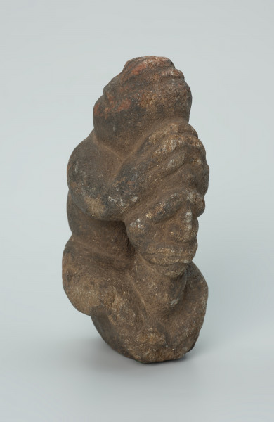 rzeźba; popiersie; Figura kultu zmarłych - Ujęcie z przodu z prawej strony. Rzeźbione w grafitowobeżowym steatycie popiersie człowieka z jaszczurką, której łapy obejmują głowę i ramiona postaci ludzkiej.