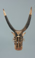 rzeźbiona maska - Ujęcie z przodu. Drewniana, rzeźbiona maska byka, do której przymocowany jest bawełniany sznurek.