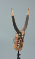 rzeźbiona maska - Ujęcie z przodu, z prawej strony. Drewniana, rzeźbiona maska byka, do której przymocowany jest bawełniany sznurek.