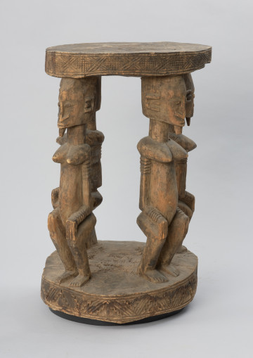 rzeźba - Ujęcie z przodu. Drewniany stół. Okrągły blat połączony z podstawą o tym samym kształcie za pomocą czterech rzeźbionych postaci.