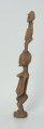 drewniana, rzeźbiona figura - Ujęcie lewego boku. Drewniana, rzeźbiona figura przedstawiająca postać człowieka niosącego na plecach drugą osobę.