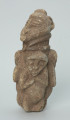 rzeźba; przedmiot obrzędowy; figura kultu zmarłych - Ujęcie z przodu z lewej strony. Rzeźbiona w szarobeżowym steatycie, otoczona trojgiem dzieci, postać ludzka o cechach kobiecych z naszyjnikiem przypominającym kryzę.