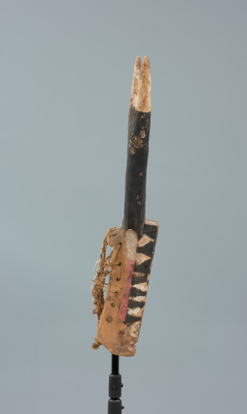 rzeźbiona maska - Ujęcie z prawego boku. Drewniana, rzeźbiona maska byka, do której przymocowany jest bawełniany sznurek.