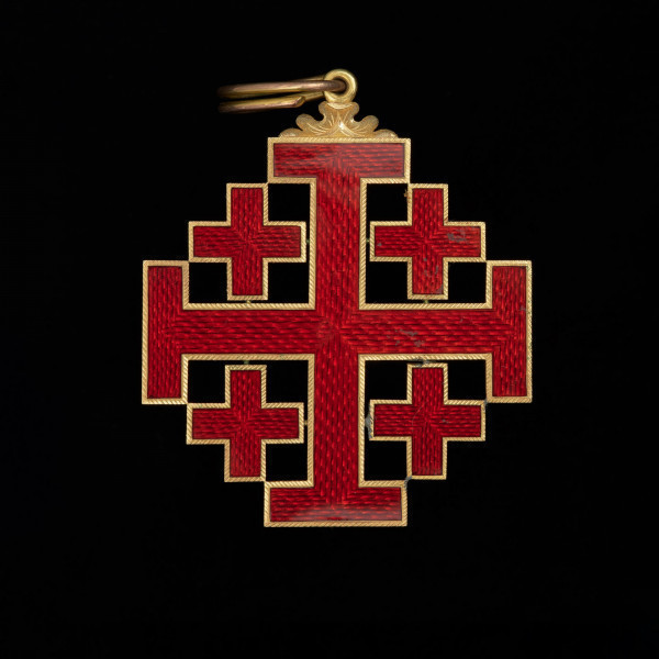 Order Grobu Świętego - Ujęcie awersu. Krzyż laskowany w kątach którego cztery krzyże greckie. Ramiona krzyży pokryte czerwoną emalią ze złotą obwódkach po brzegach. U góry motyw floralny, w którym uszko z podłużną zawieszką.