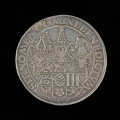 talar - Ujęcie rewersu. Na rewersie monety dziesieciopolowa tarcza herbowa przykryta trzema hełmami z klejnotami i labrami i napis w otoku.