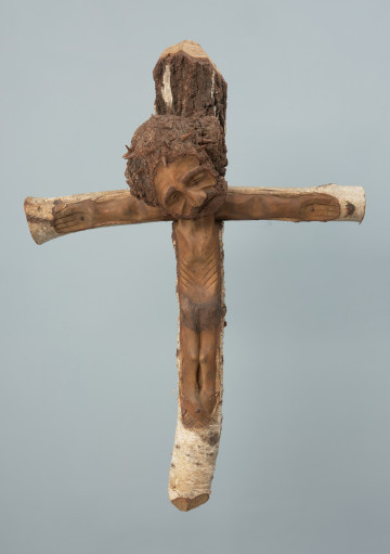 rzeźba - Ujęcie z przodu. Rzeźba - postać Chrystusa Ukrzyżowanego wpasowana w konar brzozowy, nienaturalnie duża głowa.