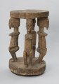 rzeźba - Ujęcie z przodu z prawej strony. Drewniany stół. Okrągły blat połączony z podstawą o tym samym kształcie za pomocą czterech rzeźbionych postaci.