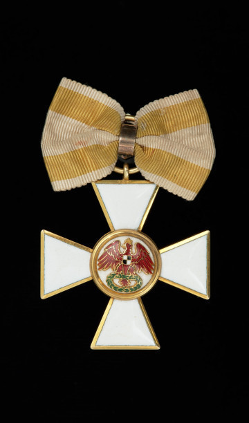 Order Czerwonego Orła III klasy - Ujęcie awersu. Krzyż maltański o ramionach pokrytych białą emalią ze złotą obwódkach po brzegach. Na awersie w środkowym medalionie na białej emalii czerwony orzeł z wieńcem laurowym w szponach.