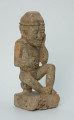Ujęcie z przodu z prawej Ustawiona na kwadratowej podstawie, wyrzeźbiona w biało-szarym kamieniu postać zamyślonego, siedzącego na stołku mężczyzny w czapce, o zaokrąglonych rogach i spłaszczonej części górnej.