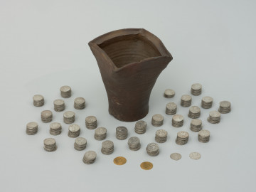 skarb monet - Ujęcie naczynia i monet ułożonych w stosiki. Skarb 656 szelągów krzyżackich i 2 guldenów niemieckich ukryty w kaflu piecowym pod koniec XV wieku.