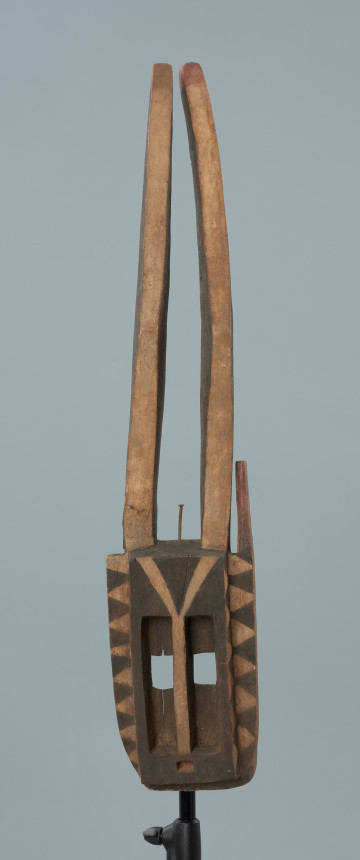 maska - Ujęcie z przodu. Drewniana, rzeźbiona maska antylopy, z dużymi geometrycznymi otworami na oczy.