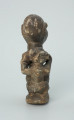rzeźba; przedmiot obrzędowy; Figura kultu sił wegetacji - Ujęcie z tyłu. Rzeźbiona w grafitowym steatycie siedząca postać ludzka o cechach kobiecych z podkurczonymi nogami i dzieckiem na plecach.