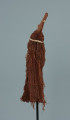 maska - Ujęcie z przodu, z lewej strony. Maska wykonana z łyka drzewa, do której przymocowany jest bawełniany sznurek.