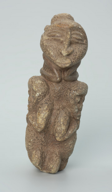 rzeźba; przedmiot obrzędowy; figura kultu zmarłych - Ujęcie z przodu. Rzeźbiona w szarobeżowym steatycie, otoczona trojgiem dzieci, postać ludzka o cechach kobiecych z naszyjnikiem przypominającym kryzę.