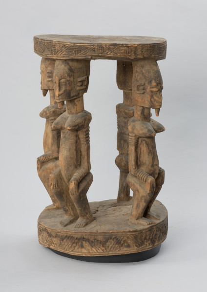 rzeźba - Ujęcie lewego boku. Drewniany stół. Okrągły blat połączony z podstawą o tym samym kształcie za pomocą czterech rzeźbionych postaci.