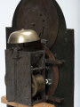 Mechanizm zegara typu szafkowego - detal; Ujęcie z tyłu fragmentu mosiężno-miedzianego mechanimu zegara. Widoczny tył tarczy zegara, oraz mechanizm alarmu.