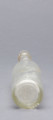 szklana butelka z wyodrębnioną szyjką z trzema pierścieniami - Ujęcie z dołu; Szklana butelka piwówka z grubego szkła butelkowego półbiałego przezroczystego. Szyjka wyodrębniona trzema wypukłymi, wąskimi pierścieniami, umieszczonymi w dolnej części szyjki. U dołu pogrubionego wylewu pogrubienia na dwa otwory do zamknięcia pałąkowego. Dno zagłębione płaskie. Zamknięcie pałąkowe. Ślad szwu bocznego.