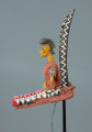 lalka teatralna: Yayoroba na antylopie dajè - Ujęcie z lewego boku. Drewniana lalka teatralna przedstawiającą kobietę siedzącą na głowie antylopy.
