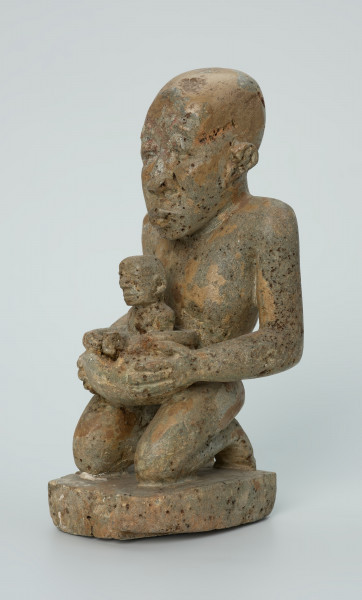 Ujęcie z przodu z lewej. Rzeźbiona w biało-szarym kamieniu postać kobiety w pozycji klęczącej. Kobieta trzyma w naczyniu dziecko. Widoczne rysy, mikropęknięcia, liczne malutkie otworki i przebarwienia.