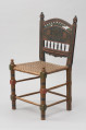 mebel - Ujęcie przodu skosem w lewą stronę. Krzesło z plecionym siedziskiem, zdobione motywem florystycznym.