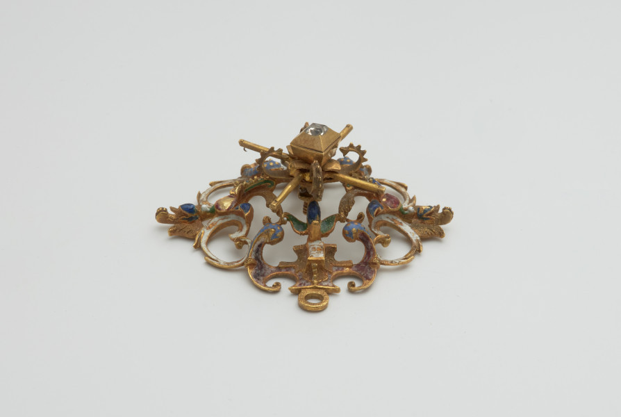 biżuteria, ozdoby - Ujęcie z boku z dołu. Ażurowy klejnot z kołpaka z diamentem i - pierwotnie -czterema perłami, zdobiony barwną emalią.