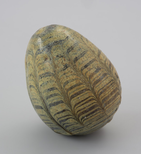 przedmiot religijny i obrzędowy - Ujęcie z przodu skosem w lewą stronę. Gliniana grzechotka w kształcie jajka, pokryta barwnym szkliwem.