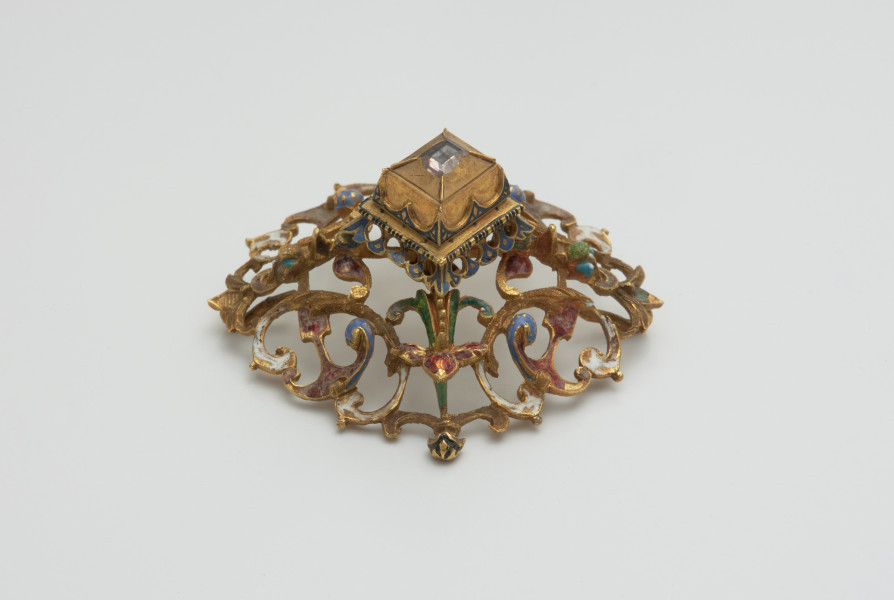 biżuteria, ozdoby - Ujęcie z boku z lewej strony. Ażurowy klejnot z kołpaka z diamentem, zdobiony barwną emalią.