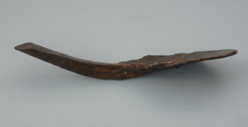 łyżka - Ujęcie tyłu łyżki skosem w prawą stronę. Łyżka drewniana z płaską nabierką i trójkątnym w przekroju trzonkiem, zdobiona.