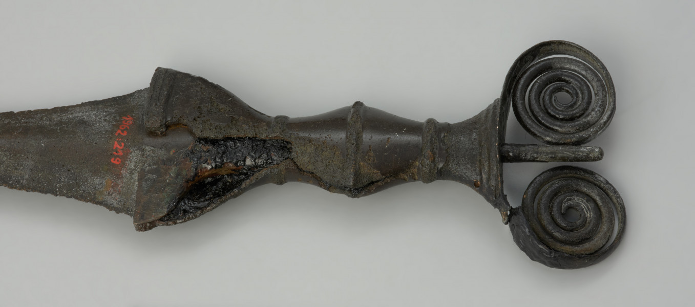 broń, miecz - Ujęcie detalu głowni z tyłu. Kompletny miecz z brązu typu antenowego z wąską głownią o odłamanym czubku.